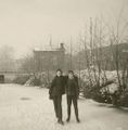 Zwei Kinder auf dem zugefrorenen Norder Tief, im Hintergrund rechts eine Betriebshalle (um 1960).